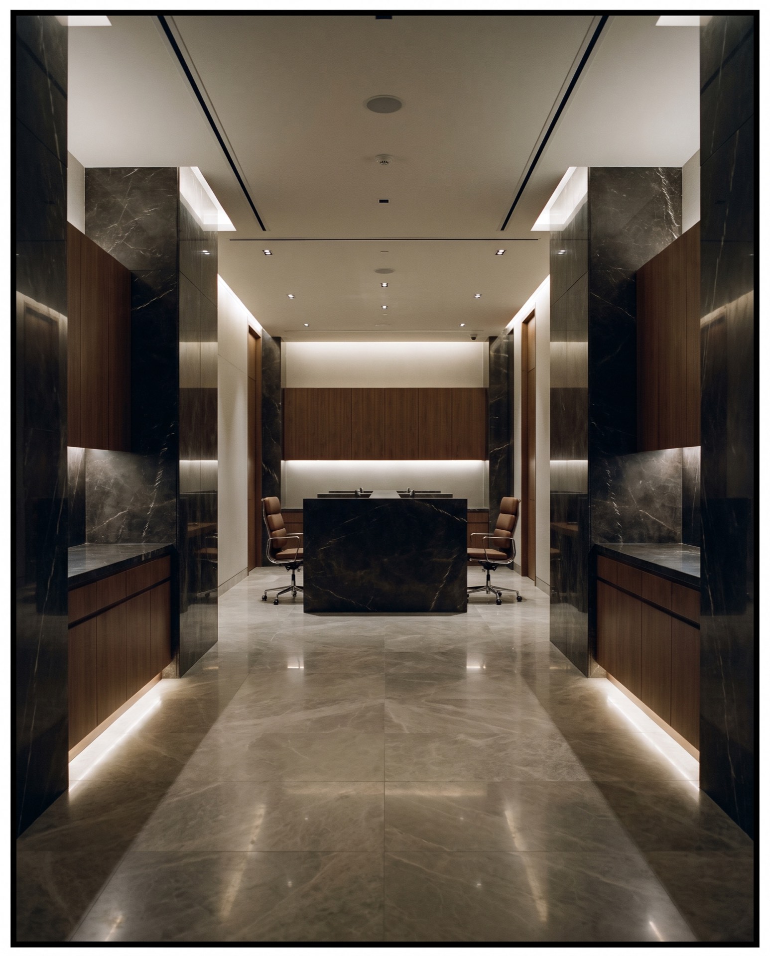 Warmly lit reception corridor with dark stone and timber finishes